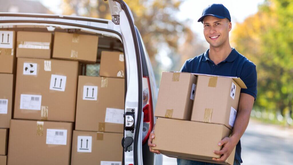 A male courier is loading boxes into the back of a delivery van providing reliable courier services