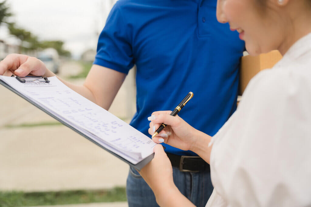 A women is signing documents on a clipboard and coordinating routed deliveries
