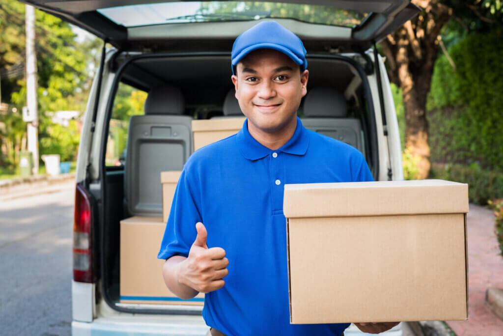 A delivery driver is holding a box that was unloaded from a fan while providing reliable delivery services