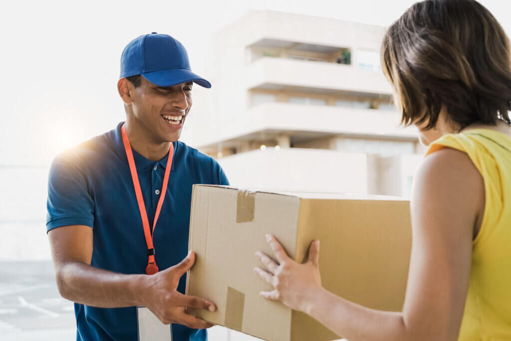 A delivery driver is handing a package to a woman and discussing an independent courier jobs