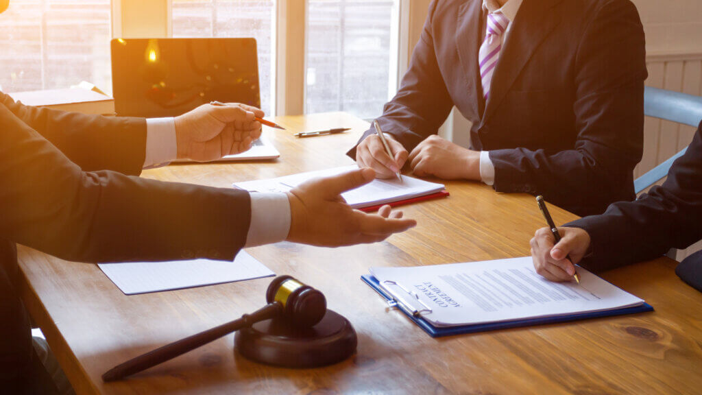 A lawyer is sitting with two clients reviewing and signing paperwork