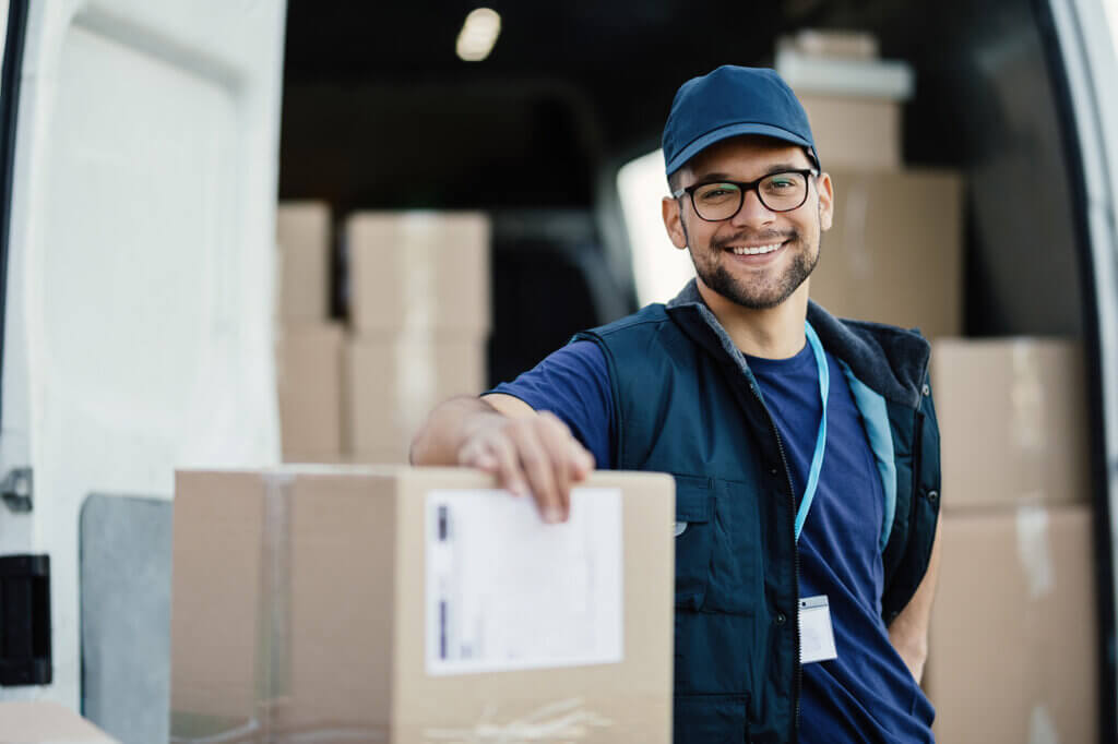 A male courier is loading packages into a van, providing same day courier services